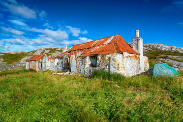 An old ruined croft with a rusty red tin roof at Quidnish