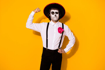Photo of creepy toreador guy show biceps hand hip challenge mad bull duel powerful victorious hero wear white shirt death costume sugar skull suspenders isolated yellow color background