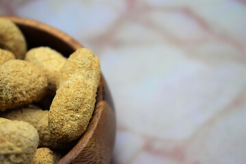 Close up, peanuts, group in wooden bowl on marble, space for text
