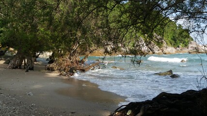 Green cliff near beautiful sea. Majestic blue sea rippling near rough green cliff of Ko Phangan on sunny day in Thailand. Exotic Tropical Paradise Beach.