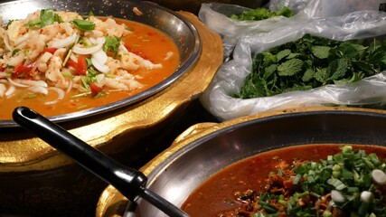 Bowls with various Asian dishes on stall. Bowls of assorted traditional Thai dishes placed on stall of street diner in evening. Oriental night market food court.