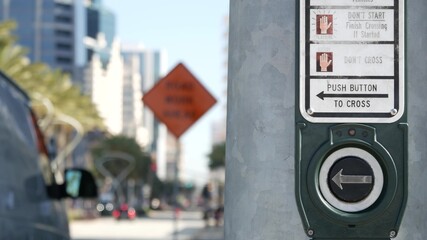 Traffic light button on pedestrian crosswalk, people have to push and wait. Traffic rules and regulations for public safety in USA. Zebra street crossing on road intesection in San Diego, California
