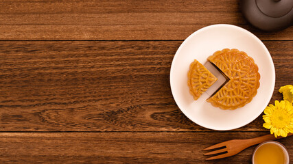 Moon cake for Mid-Autumn Festival, delicious beautiful fresh mooncake on a plate over dark wooden background table, top view, flat lay layout design concept.