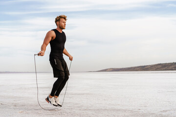 Image of caucasian athletic sportsman working out with jumping rope