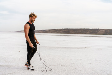 Image of caucasian athletic sportsman working out with jumping rope