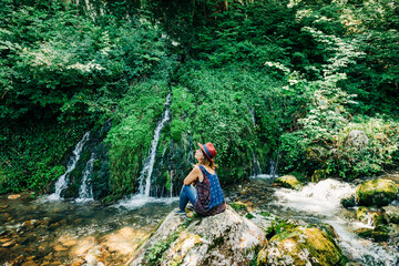 Obraz premium Young female nature explorer enjoying by the waterfalls