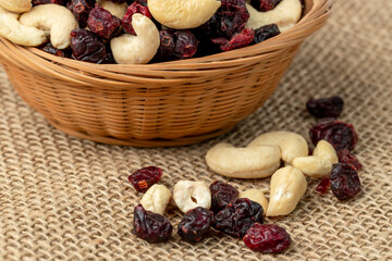 Cashews and cranberries. Mix of nuts and dried fruits in a basket on burlap.