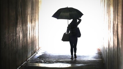 Illustration style enhanced silhouette of a woman holding an umbrella emerging from a tunnel. Wet weather working city chic lifestyle. Weather forecast confidence . 