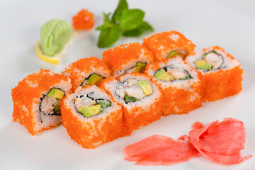 Суши красиво выложены дополнительными ингредиентами снятые на белом фоне