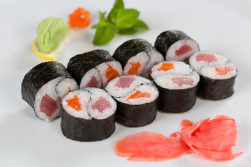 Суши красиво выложены дополнительными ингредиентами снятые на белом фоне