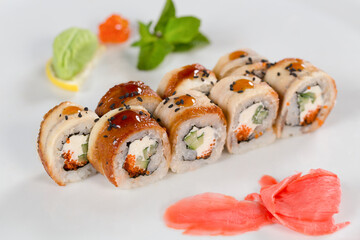 Суши красиво выложены дополнительными ингредиентами снятые на белом фоне