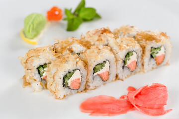 Суши красиво выложены дополнительными ингредиентами снятые на белом фоне