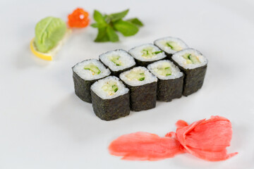 Суши красиво выложены дополнительными ингредиентами снятые на белом фоне