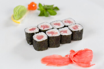 Суши красиво выложены дополнительными ингредиентами снятые на белом фоне