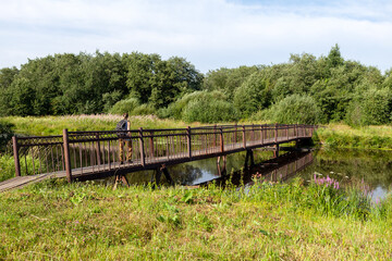 A tourist walks on a pedestrian wooden bridge over the river