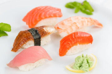 Суши красиво выложены дополнительными ингредиентами снятые на белом фоне