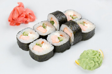 Суши красиво выложены дополнительными ингредиентами снятые на белом фоне