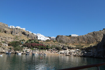 Fototapeta na wymiar Harbour still water with boats. Hills with white pretty houses. Lindos Greece