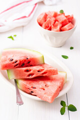 Juicy ripe sweet red watermelon slices with mint in a plate on a white background