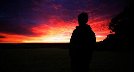 Fototapeta premium silhouette of young man with colorful sky clouds, sunset time, 