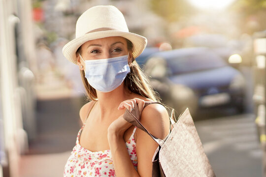 Young Woman Doing Shopping In Tourist Area, Wearing Face Mask