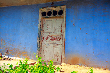 Old closed door of abandoned house . Rustic house painted in blue 