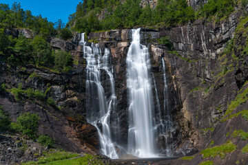 Fototapeta na wymiar Skjervsfossen waterfall, on the road between Granvin and Voss, Hordaland, Norway. Impressive beautiful win falls plunging 150 metres in a narrow canyon