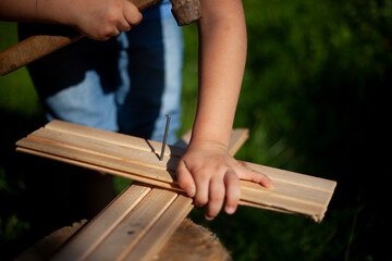 Child girl hammers a nail into the board.