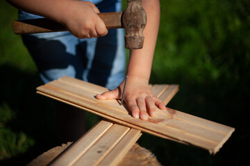 Child girl hammers a nail into the board.