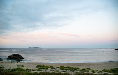 Photo of the beach in Galicia during sunrise. Beautiful pink and yellow clouds, empty beach....