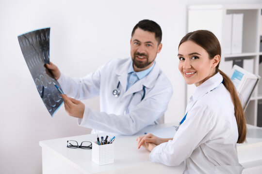 Orthopedists examining X-ray picture at desk in clinic
