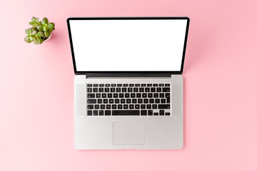 Fototapeta na wymiar Laptop with blank display on pink table with flower. Office desktop. Top view