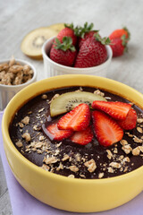 Brazilian typical acai bowl with fruits and muesli over wooden background