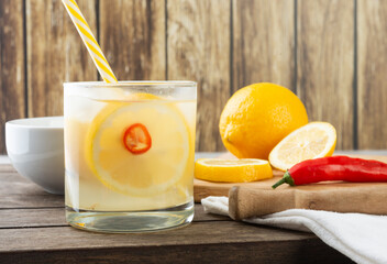 Brazilian sicilian lemon and red chili caipirinha in a glass with ice with fruit slices over wooden board