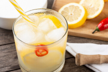 Brazilian sicilian lemon and red chili caipirinha in a glass with ice with fruit slices over wooden board
