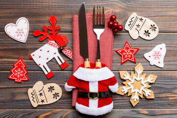 Top view of new year utensils on napkin with holiday decorations and reindeer on wooden background. Close up of christmas dinner concept