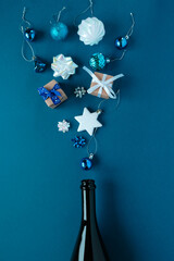 Champagne bottle with different christmas decoration on blue. 