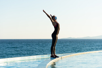 Obraz premium Young woman with protective surgical face mask performing yoga stretching exercises outdoor during covid-19 coronavirus pandemic