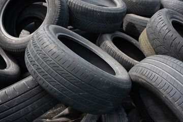 Obraz premium Industrial landfill for the processing of waste tires and rubber tyres. Pile of old tires and wheels for rubber recycling. Tyre dump