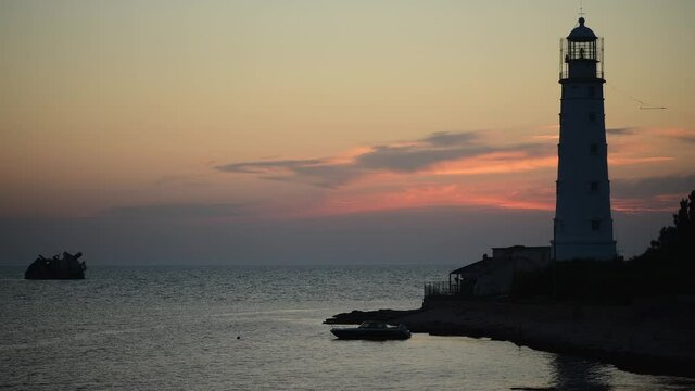 Amazing colourful time lapse sunset at ocean near old Lighthouse and sunken ship