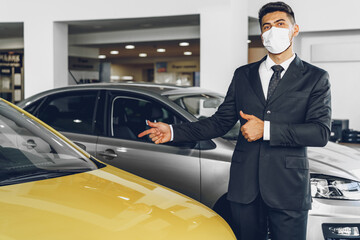 Man car dealer wearing protective medical mask on his working place