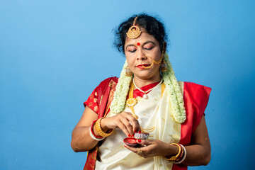 Married Indian Bengali brunette woman wearing traditional red and white sari is looking her face in...