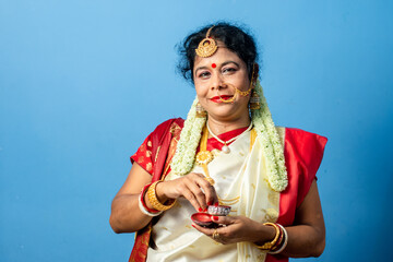 Married Indian Bengali brunette woman wearing traditional red and white sari is looking her face in...