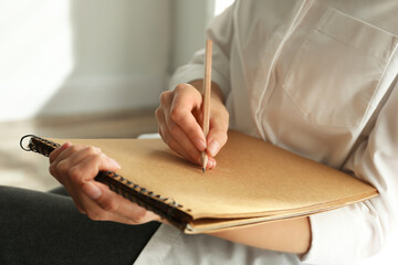 Woman drawing with pencil in notepad, closeup