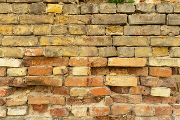 a very old crumbling wall made of yellow and orange stones