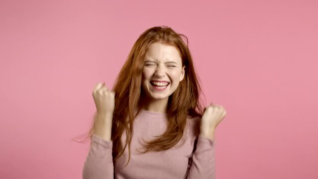 Girl with beautiful hair very glad and happy, she showing yes, gratitude gesture. Excellent news. Surprised excited happy woman on pink background
