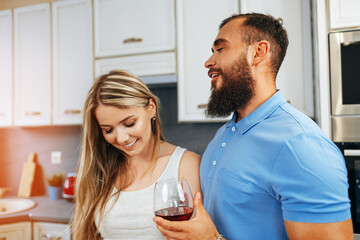Cheerful smiling couple cooking and drinking wine in kitchen