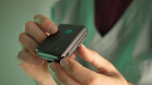 80s 90s vintage pager beeper being used by a doctor or nurse wearing a uniform. The pager is still used today in many medical facilities.