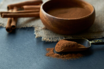 cinnamon sticks, tied with jute rope in rustic style. Ground cinnamon in a wooden bowl and vintage scoop. Close up on a black background. copy space for text. side view, flat lay.