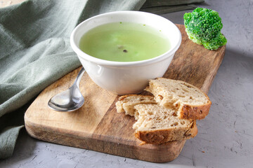 Broccoli soup in white plate over wooden background